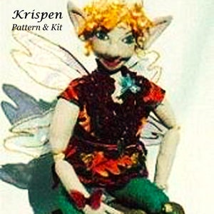 Könnte beinhalten: Eine handgefertigte Feenpuppe mit einem skurrilen Design. Die Puppe hat ein bordeauxfarbenes Oberteil mit orangefarbenen Akzenten, grüne Hosen und rote Schuhe. Die Puppe hat einen hellen Hautton, blondes Haar und große Ohren. Die Puppe sitzt auf einem grünen Felsen. Der Text "Krispen Pattern & Kit" befindet sich oben links.