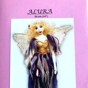 May include: A handmade doll named Alura, 35 cm tall, with blonde hair, a gold bodice, and a layered purple and white dress. The doll has delicate wings and is an original design by Michelle Munzone.