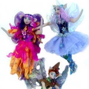 May include: Three handmade fairy dolls with wings, each with a different color scheme and outfit. The fairies are made of fabric and have painted faces.