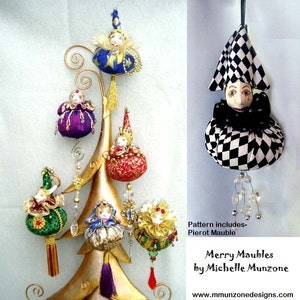 May include: A set of six handmade fabric ornaments shaped like jesters. The ornaments are decorated with various colors and patterns, including red, gold, green, blue, and purple. The ornaments are hanging from a gold metal tree stand. The text "Merry Maubles by Michelle Munzone" is printed below the ornaments.