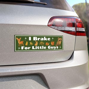 May include: Green bumper sticker with the text "I Brake For Little Guys" and illustrations of a deer, duckling, frog, rabbit, turtle, snail, squirrel, and raccoon. The sticker is rectangular and has a white border.