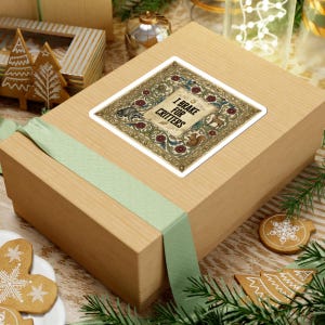 May include: A square sticker with the text "I Brake for Critters" in a decorative frame featuring a raccoon and squirrel. The sticker is on a light brown box with a green ribbon, surrounded by holiday decorations.