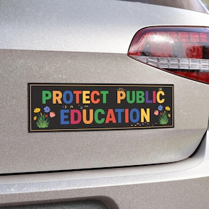 Pode incluir: Um autocolante retangular preto com as palavras "PROTECT PUBLIC EDUCATION" em letras coloridas. O autocolante tem uma borda amarela e detalhes florais. Está afixado na parte traseira de um carro cinzento.