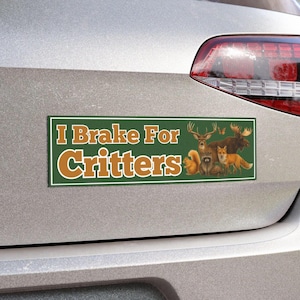 May include: Green and white bumper sticker with the text "I Brake For Critters" in brown lettering. The sticker features illustrations of various animals, including a deer, moose, fox, squirrel, and raccoon.