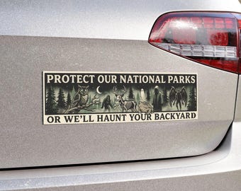 May include: Rectangular bumper sticker with the text "PROTECT OUR NATIONAL PARKS OR WE'LL HAUNT YOUR BACKYARD." The sticker features illustrations of an owl, Bigfoot, a deer skeleton, a frog, and other spooky creatures.