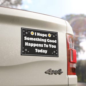 Pu&ograve; includere: Un magnete rettangolare nero per auto con testo bianco che recita "I Hope Something Good Happens To You Today". Il magnete ha un bordo bianco ed &egrave; decorato con piccole stelle e grafiche floreali. Il magnete &egrave; attaccato alla parte posteriore di un veicolo bianco.