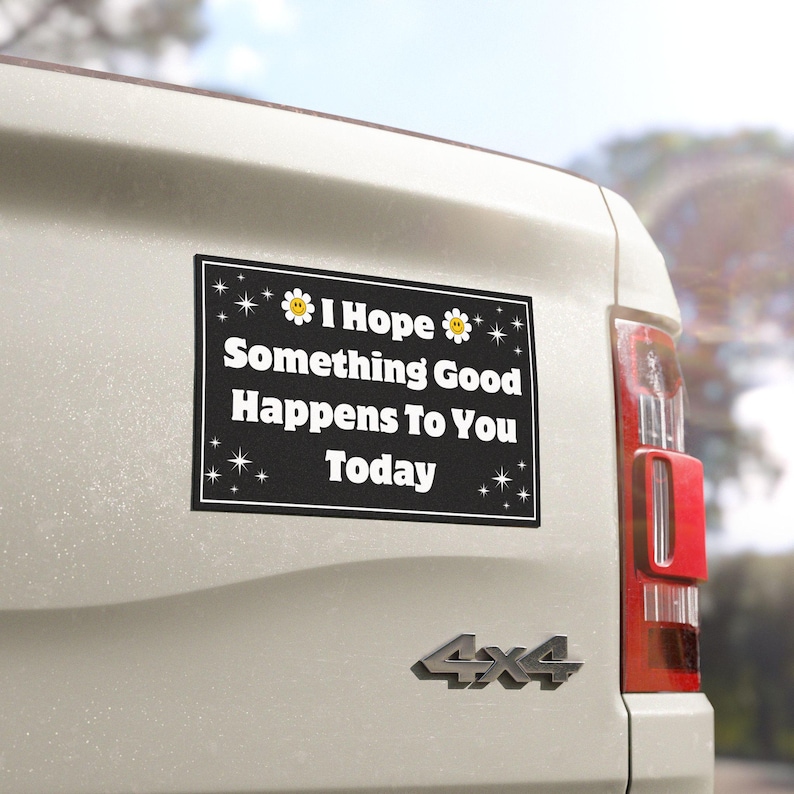 Pu&ograve; includere: Un magnete rettangolare nero per auto con testo bianco che recita "I Hope Something Good Happens To You Today". Il magnete ha un bordo bianco ed &egrave; decorato con piccole stelle e grafiche floreali. Il magnete &egrave; attaccato alla parte posteriore di un veicolo bianco.