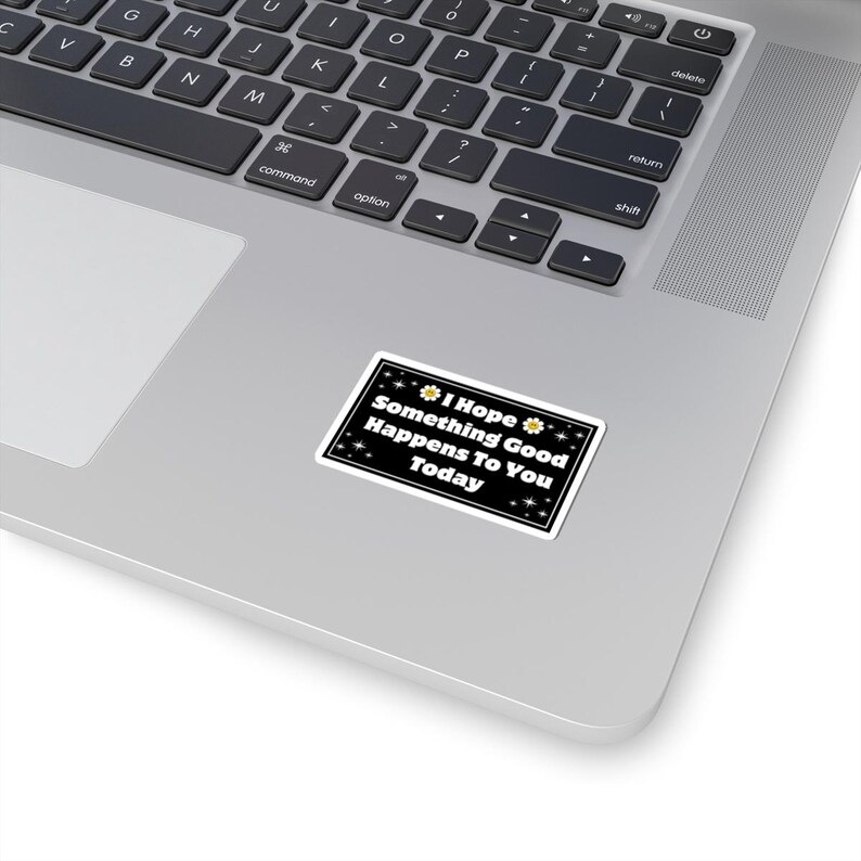 Pu&ograve; includere: Un adesivo rettangolare con sfondo nero e bordo bianco &egrave; posizionato su un laptop. L'adesivo riporta la scritta "I Hope Something Good Happens To You Today" in bianco, con decorazioni a margherita e stella.