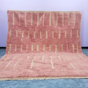 May include: A rectangular area rug featuring a deep rose pink shaggy pile texture. The surface is decorated with a repeating pattern of vertical, off-white dashed lines arranged in horizontal rows across the entire length of the rug.