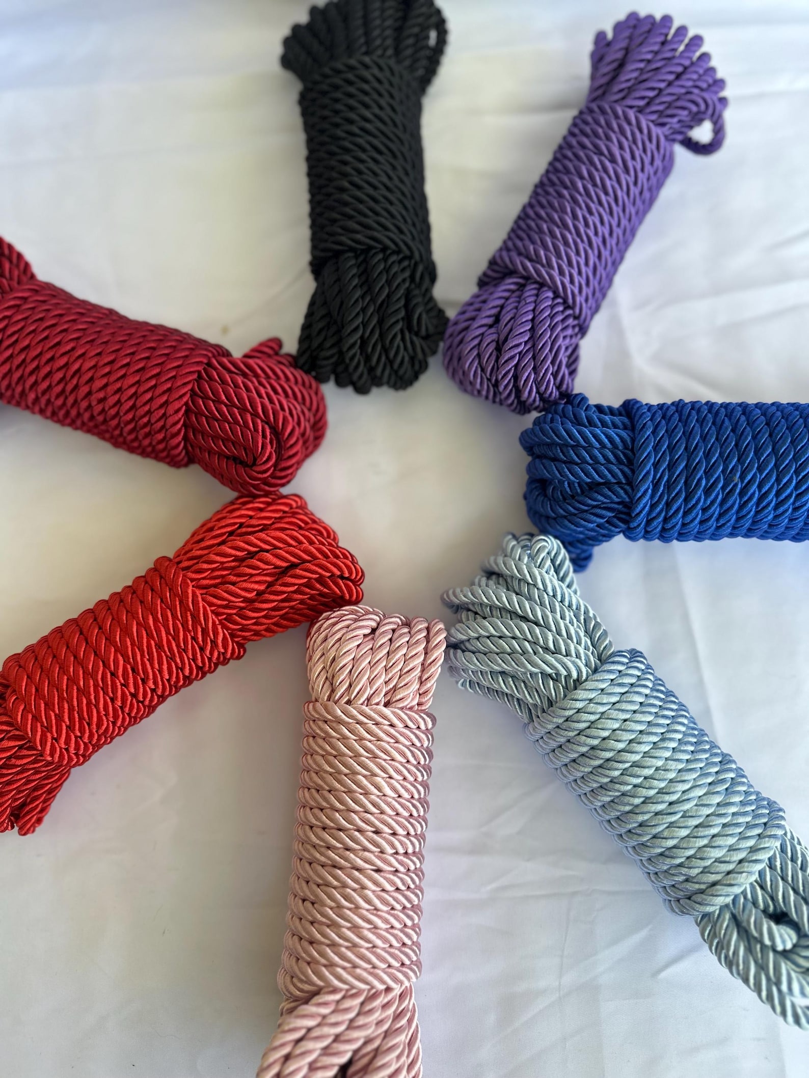 Silk shibari ropes in multiple vibrant colors coiled neatly for bdsm ties, bondage restraints, and sensual rope bondage play.