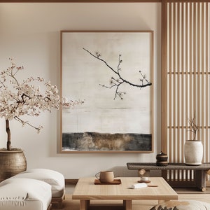 May include: A minimalist living room with a low coffee table, a white sofa, and a large framed print of a branch with blossoms. The room has a Japanese aesthetic with a wooden screen and a vase with a plant.