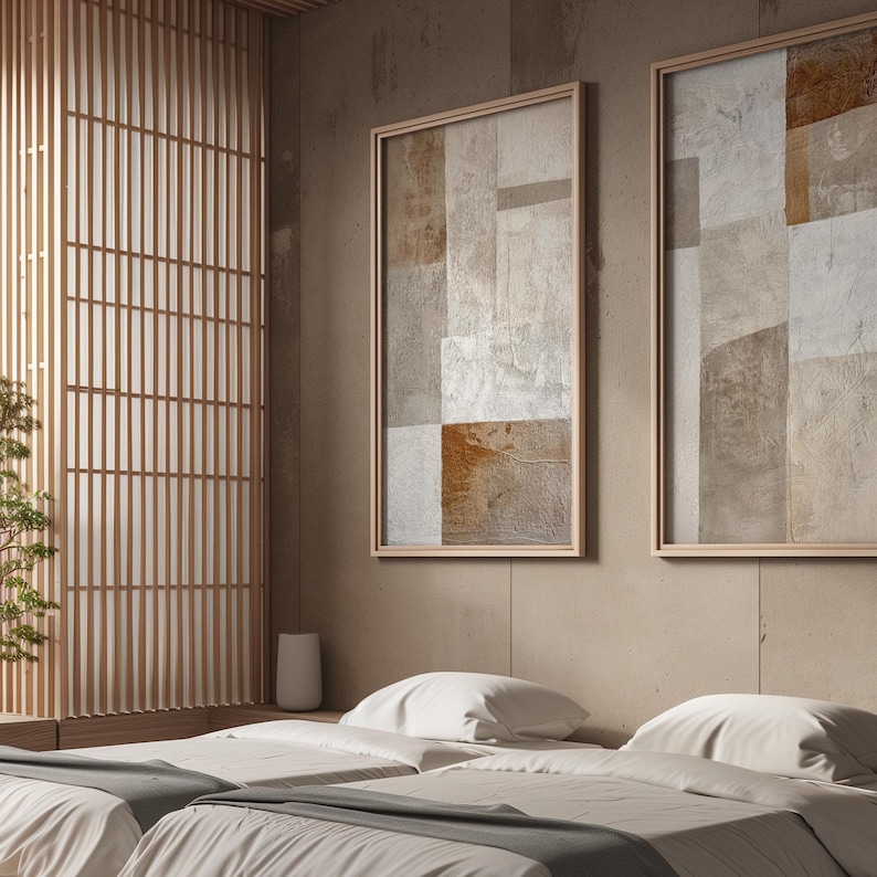 May include: Two abstract paintings with a beige and brown color scheme hang on a wall above a bed with white linens. The bed is in a room with a wooden slatted wall.