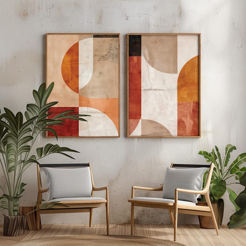 May include: Two framed abstract art prints with geometric shapes in shades of orange, red, beige, and white. The artwork hangs above two wooden chairs with gray cushions, creating a modern and minimalist interior design.
