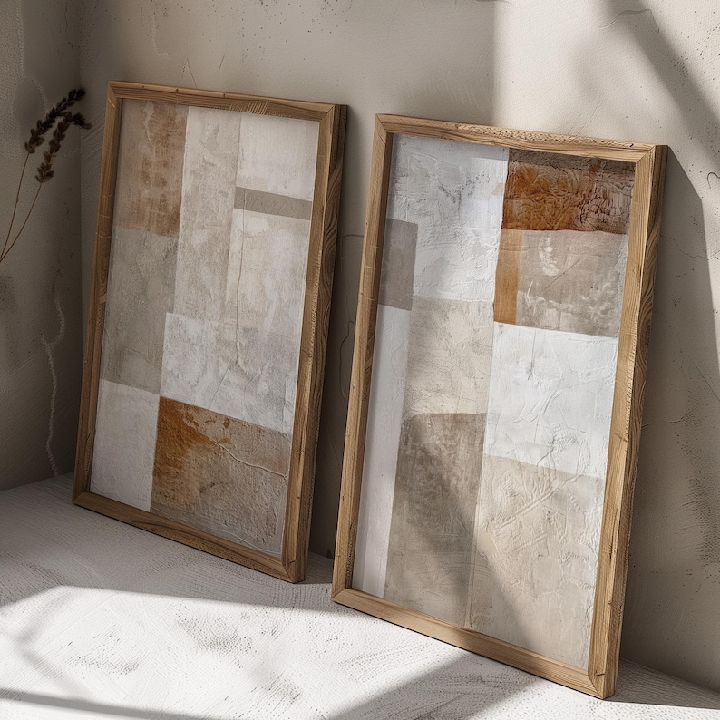 May include: Two framed abstract art prints with a neutral color palette of beige, brown, and white. The prints are in wooden frames with a natural finish.