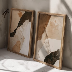 May include: Two framed abstract art prints with a brown, white, and green color scheme. The prints are in wooden frames with a natural wood finish.