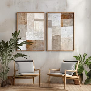 May include: Two abstract paintings in beige, brown, and white tones are displayed on a wall above two wooden chairs with light gray cushions. The chairs are positioned on a light brown rug.