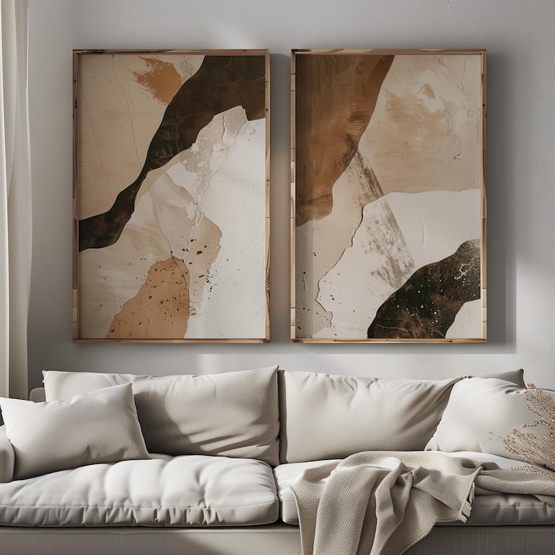 May include: Two abstract art prints in wooden frames. The prints feature a brown, beige, and white color scheme with abstract shapes and textures.