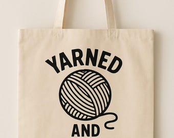 May include: A cream-coloured tote bag featuring the text "Yarned and Dangerous" in black, with a graphic of a ball of yarn. The bag has two handles and is made of a sturdy fabric, ideal for carrying items.
