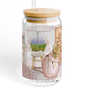 Puede incluir: Un vaso de vidrio transparente con tapa de madera y pajita transparente. El vaso presenta una ilustración en acuarela de un conejo con un vestido rosa en una habitación con ventana. La habitación tiene chimenea y taburete.