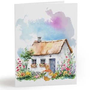 May include: A folded greeting card featuring a watercolor illustration of a quaint cottage with a thatched roof, surrounded by colorful flowers. A rabbit with a basket stands near the door. The background has a soft watercolor wash of blue and pink.