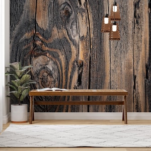 May include: A wooden bench with a natural wood finish sits in front of a wall with a wood grain pattern. The wall has a dark brown and black colour scheme.