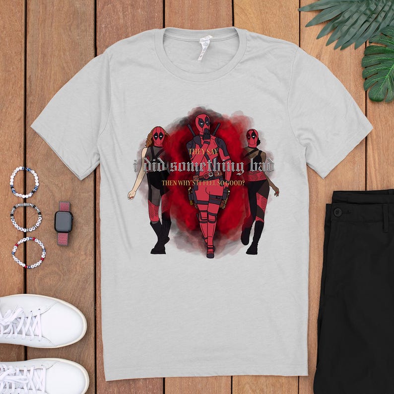 May include: A gray t-shirt with a graphic of three figures in red and black superhero costumes. The text on the shirt reads "They say I did something bad. Then why still feel so good?"