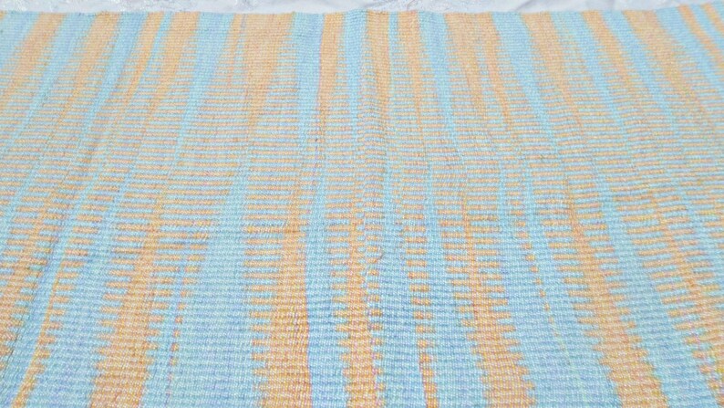 May include: A woven rug with alternating stripes of light blue and peach.