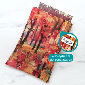 May include: A rectangular case featuring a vibrant autumn forest design. The case includes a label that reads "Angela". The text "with optional personalisation" is also visible.