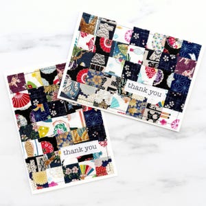 May include: Two handmade greeting cards with a patchwork design. The cards feature a variety of fabric patterns in red, blue, white, and yellow. Each card has the words "thank you" printed on a white label.