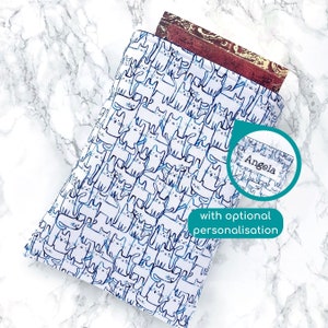 May include: White book sleeve with a blue and black cat pattern. The sleeve has a personalised name, "Angela", on the side. The text "with optional personalisation" is also visible.