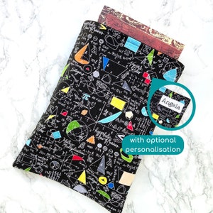 May include: Black book cover with a white and colourful geometric pattern of maths equations and symbols. The cover has a small white label with the name "Angela" printed on it.