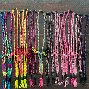 Puede incluir: Una colecci&oacute;n de 15 cordones trenzados de colores con clips de pl&aacute;stico negro. Los cordones est&aacute;n hechos con paracord de diferentes colores y presentan varios patrones y dise&ntilde;os.
