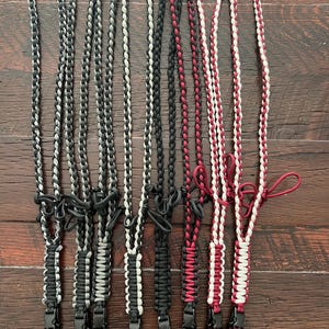 Puede incluir: Ocho cordones trenzados en combinaciones de colores negro, blanco y rojo. Cada cord&oacute;n tiene un clip de pl&aacute;stico negro en el extremo.