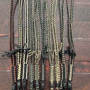 Puede incluir: Diez cordones de paracord diferentes con clips negros. Los cordones est&aacute;n hechos con diferentes combinaciones de colores de paracord negro, marr&oacute;n, beige y verde.
