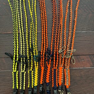 Puede incluir: Ocho cordones de paracord diferentes con varias combinaciones de colores, incluyendo negro y amarillo, negro y verde, negro y naranja, y camuflaje. Cada cord&oacute;n tiene un clip de pl&aacute;stico negro en el extremo.