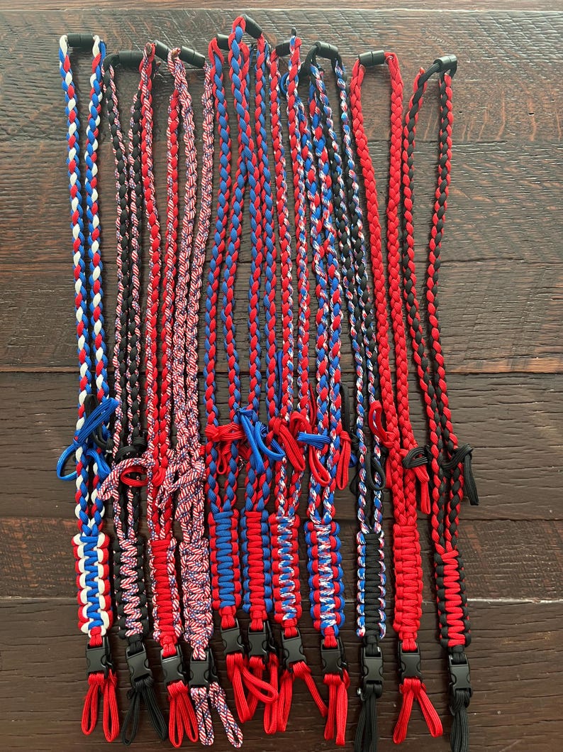 Puede incluir: Una colecci&oacute;n de 13 cordones trenzados en combinaciones de colores rojo, blanco y azul. Los cordones est&aacute;n hechos de paracord y tienen un cierre de pl&aacute;stico negro en el extremo.