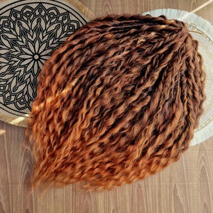 Puede incluir: Un conjunto de extensiones de cabello largas, rizadas y ombré en tonos marrones y cobrizos.