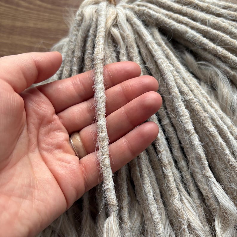 Puede incluir: Un paquete de rastas sint&eacute;ticas de color rubio claro. Las rastas est&aacute;n hechas de un material suave y texturizado y tienen un aspecto natural ligeramente ondulado.