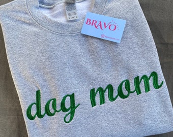 Könnte beinhalten: Grauer Pullover mit grünem Sticktext, der "dog mom" lautet.