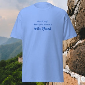 May include: A light blue t-shirt with the text "Maketh way! Seeth yond I am on a Side Quest" in a blue, gothic font.