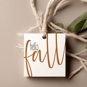 May include: White gift tag with the text "hello fall" in brown cursive lettering. The tag is tied with twine.