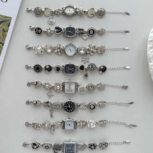 Puede incluir: Una colección de pulseras de reloj plateadas con diferentes esferas y dijes decorativos. Los dijes incluyen estrellas, lunas y flores. Las esferas tienen diferentes formas, incluyendo redondas, cuadradas y rectangulares. Las pulseras son de metal.
