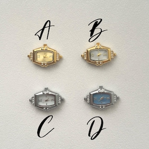 May include: Four small, rectangular watch faces with Roman numeral hour markers. Two are gold-toned with white or gold faces, and two are silver-toned with white or blue faces. The letters A, B, C, and D are written above and below the watches.