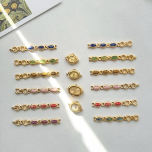 K&ouml;nnte beinhalten: Eine Sammlung goldfarbener Uhrenarmb&auml;nder und kleiner Uhren mit verschiedenfarbigen, oval geformten Steinen. Die Armb&auml;nder weisen blaue, gr&uuml;ne, braune, rosa, rote und violette Steine auf. Die Uhren haben goldene Zifferbl&auml;tter.