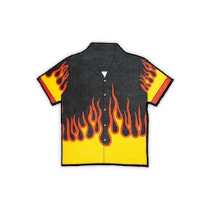 May include: A black short-sleeved shirt with a yellow and orange flame design. The shirt has a button-up collar and a pocket on the left side.