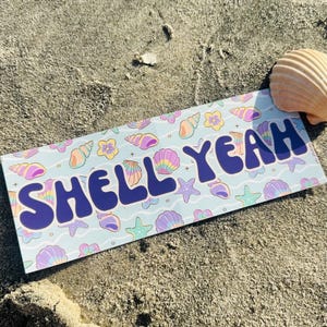 May include: A rectangular sticker with a light blue background featuring a repeating pattern of colorful seashells, starfish, and flowers. The text SHELL YEAH is printed in large, bold, dark blue letters across the center of the sticker.