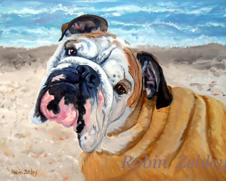 May include: A painting of a bulldog with a white and brown coat, looking to the side with its tongue sticking out. The dog is on a beach with blue water in the background. The painting is signed "Robin Zebbley".