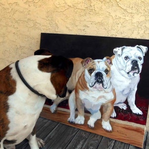 K&ouml;nnte beinhalten: Ein Gem&auml;lde von drei Bulldoggen, eine wei&szlig;e und zwei braun-wei&szlig;e, auf einem roten Teppich vor einem schwarzen Hintergrund. Ein vierter Hund, ein Boxer, ist im Vordergrund und betrachtet das Gem&auml;lde. Das Gem&auml;lde befindet sich auf einem Holzrahmen.