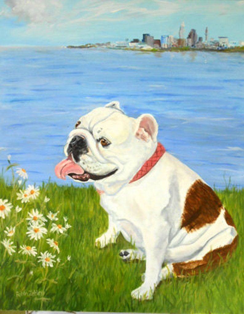 May include: A white and brown bulldog with a pink collar sits in a grassy field with white daisies. The dog is looking to the left of the image. The background is a blue lake with a city skyline in the distance.