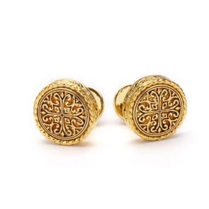 May include: A pair of gold cufflinks with a circular design featuring an intricate, engraved floral pattern.